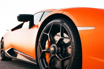 An orange sports car with a black wheel on asphalt.